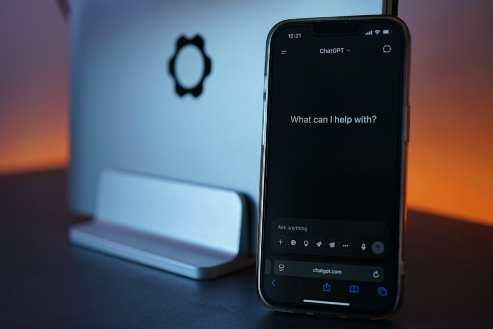 ノートパソコンの横にChatGPTを表示したスマートフォン