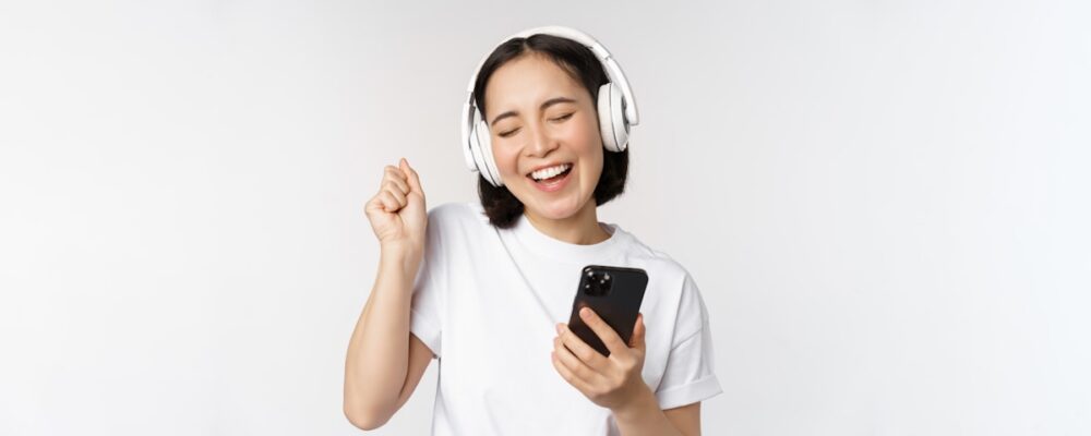 屋外でヘッドホンをつけてスマホを見る女性