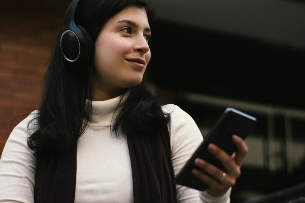 ヘッドホンでスマホの音声を聞く女性